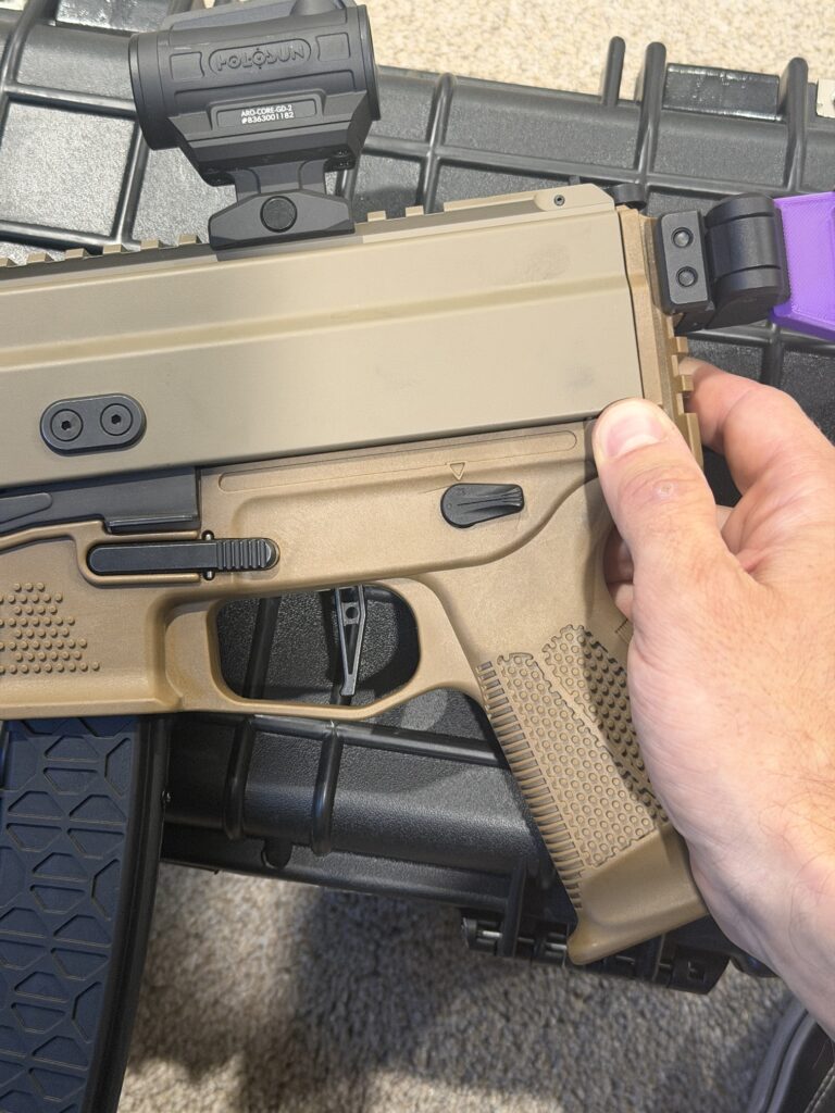 Hand on the rear of a Grand Power Stribog SP9A3 with the lower frame still attached, before swinging it away